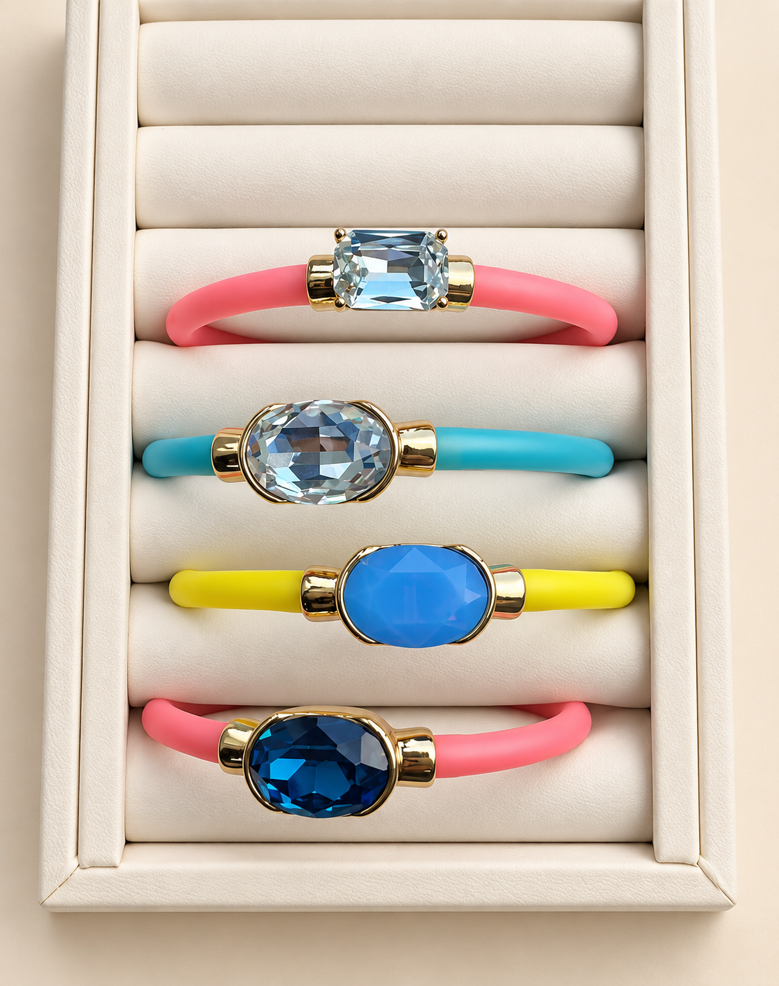 Four colorful gemstone bracelets on an ivory jewelry display