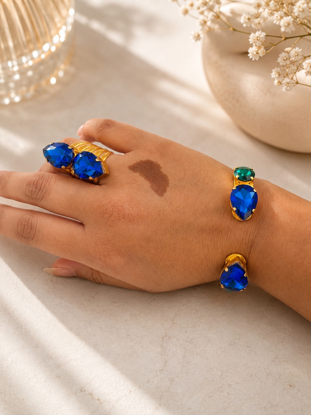Blue and green gemstone jewelry displayed on a hand